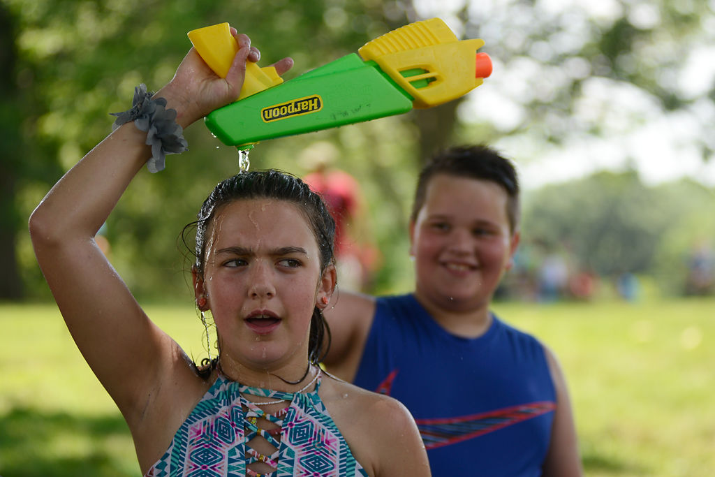 Hayley Taylor, 11, and Lance Schommer, 9, finish their water gun fight by dumping left over water on Taylor's head